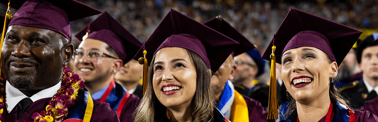 ASU students in caps and gowns smiling at a graduation ceremony