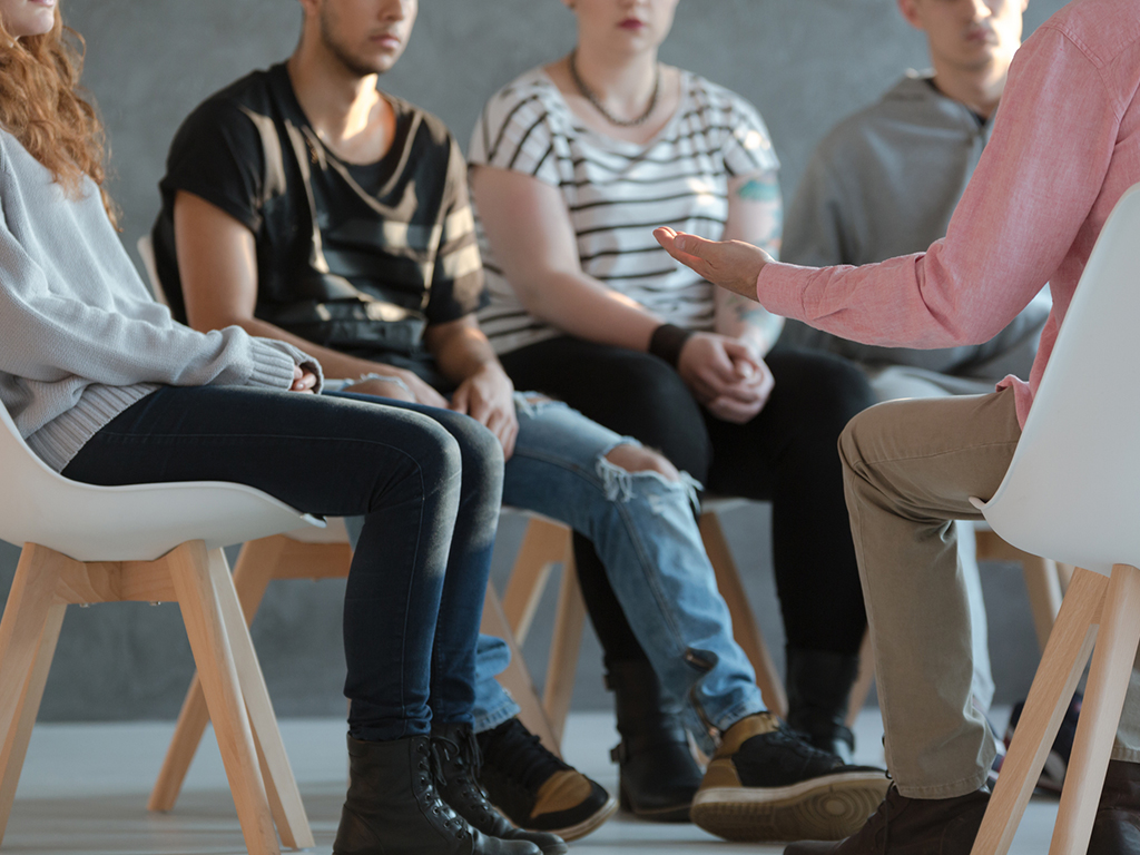 young adults sitting in chairs in a circle and talking