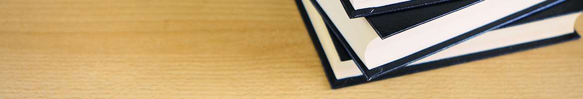 stack of black books on a wooden surface