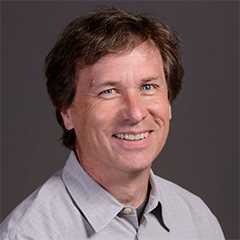Eric Welch headshot - fair-skinned man, smiling, brown hair, gray collared shirt