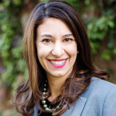 Andrea Whitsett headshot - fair-skinned woman, smiling, brown hair, gray blazer, black shirt, necklace
